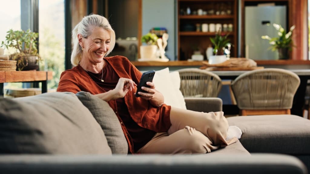 Mature woman in the phone laughing on sofa