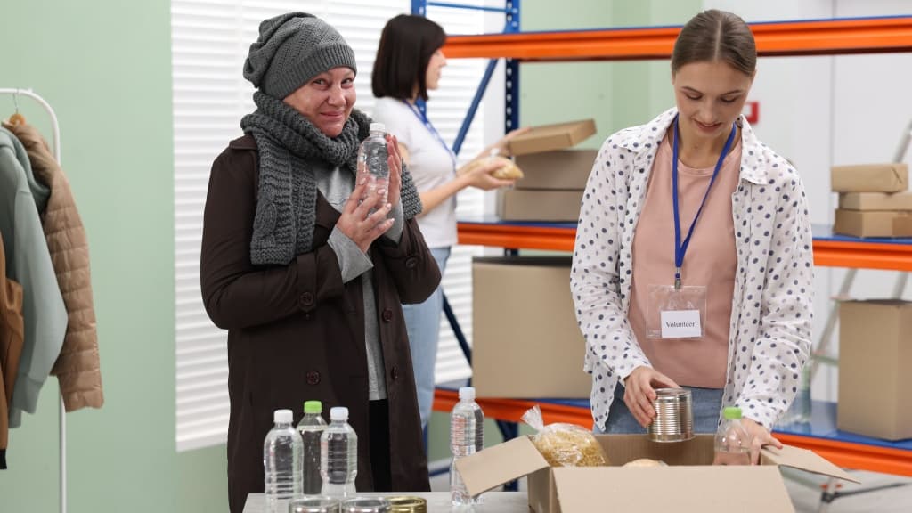 Volunteers helping homeless senior woman in shelter