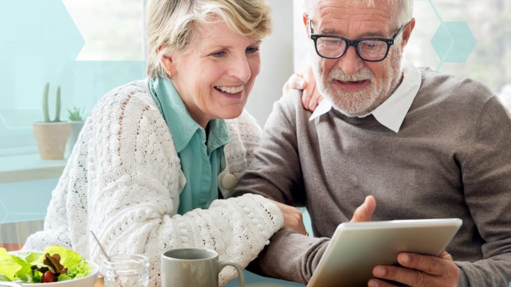 This is an image of a couple enjoying time together, smiling while looking at a tablet.