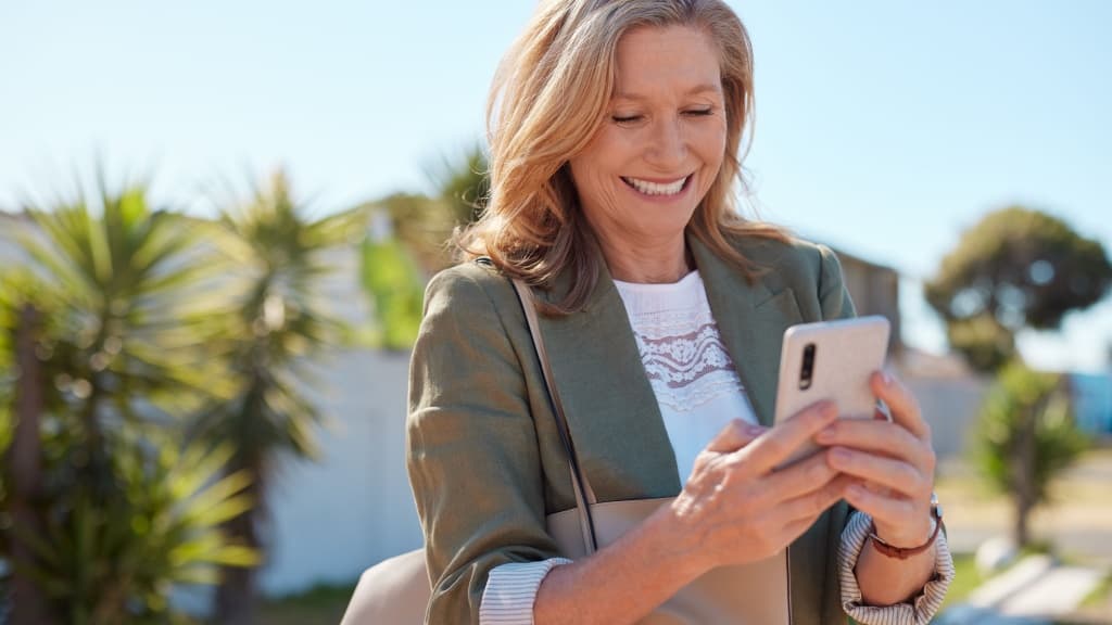 Stylish senior woman smiling at phone.