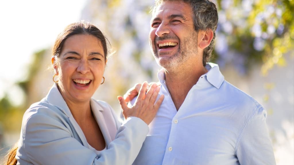 Close-up of a cheerful couple laughing together outdoors in bright sunlight